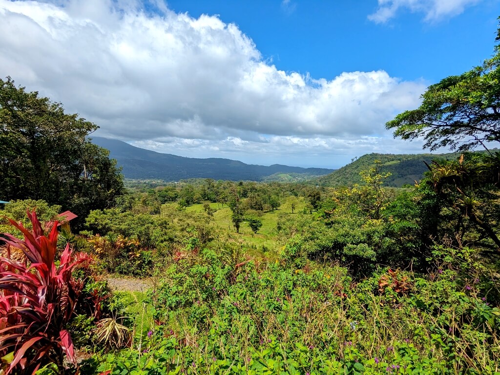 Scenic view capturing the gardens in the foreground, the valley of Bijagua in the midground, and the mountains adjacent to the Miravalles Volcano in the background.