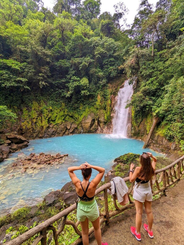 Two travelers admiring Rio Celeste Waterfall.