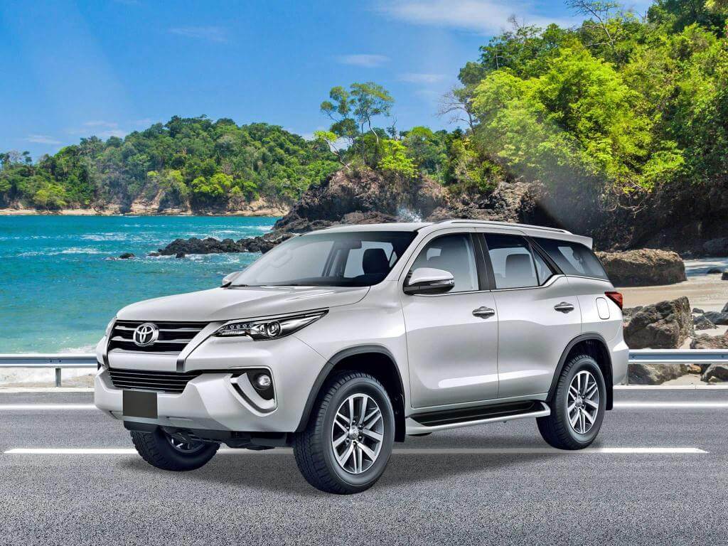 Toyota Fortuner rental SUV parked in front of a scenic coastal view