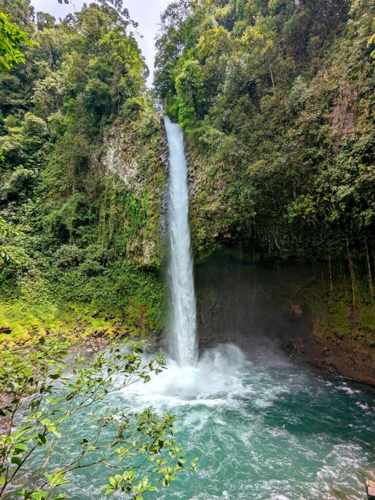 Vertical view of La Fortuna Waterfall, emphasizing its height, pool, and lush surroundings.