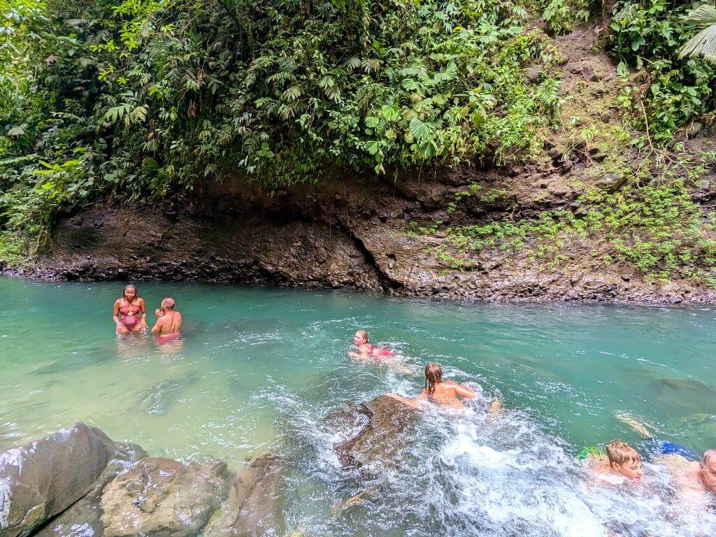 People swimming in the calm blue waters of La Fortuna River near La Fortuna Waterfall.