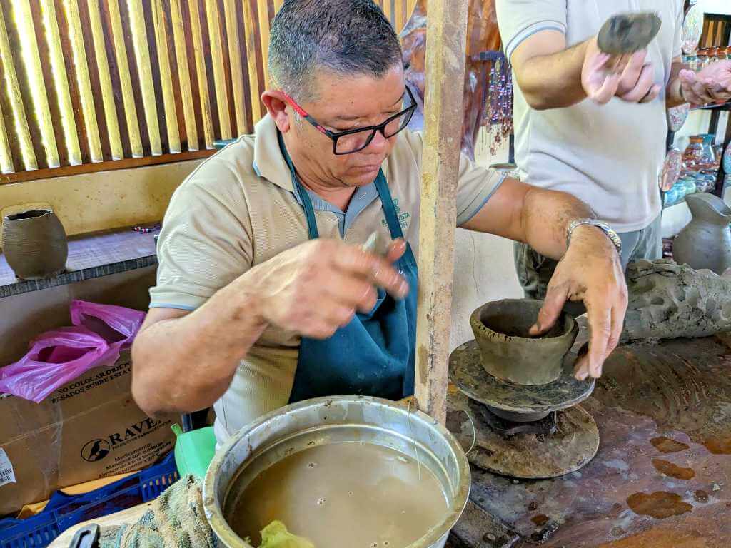 Experienced artisan working clay pottery, demonstrating the traditional style and historical importance to a traveler in Costa Rica.