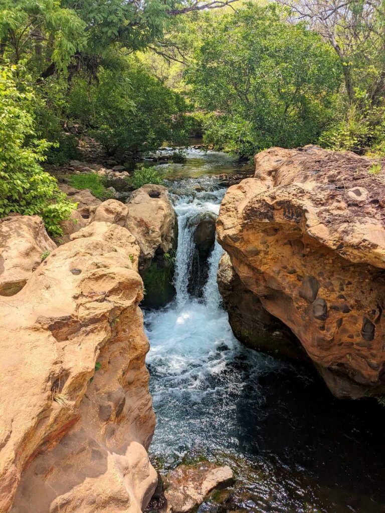 Small waterfall surrounded by volcanic rock at Poza Los Coyotes, foothills of the Guanacaste Volcanic Mountain Range.