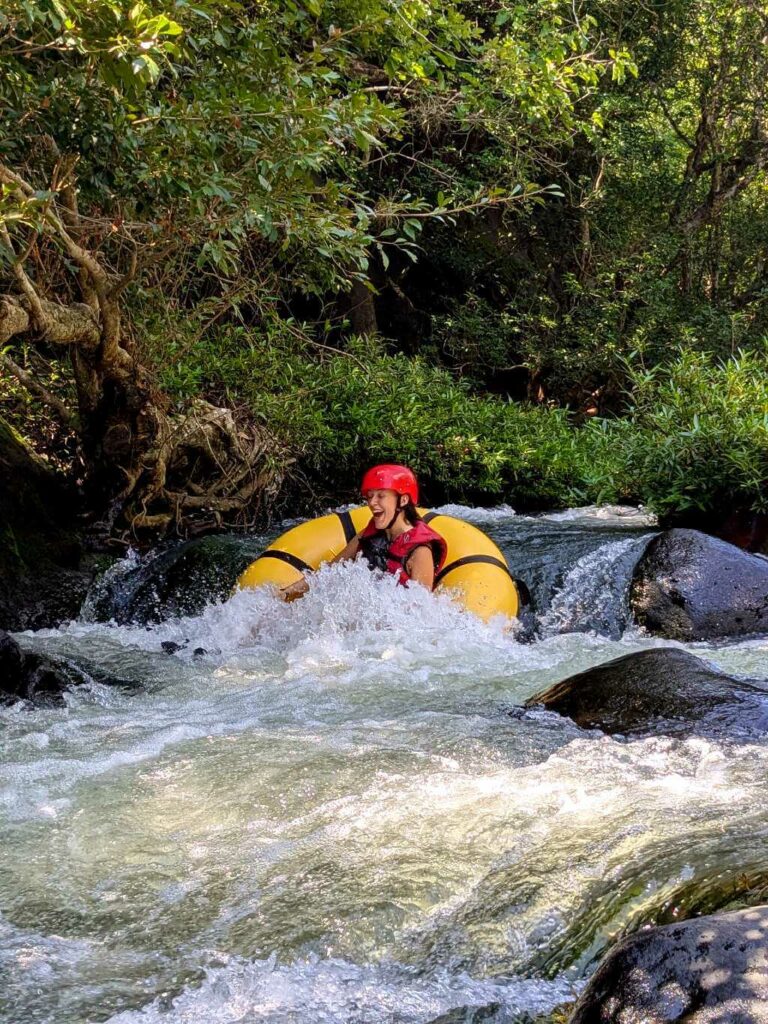 Traveler tubing down Rio Colorado through riparian forest with a mix of slow and rapid sections.