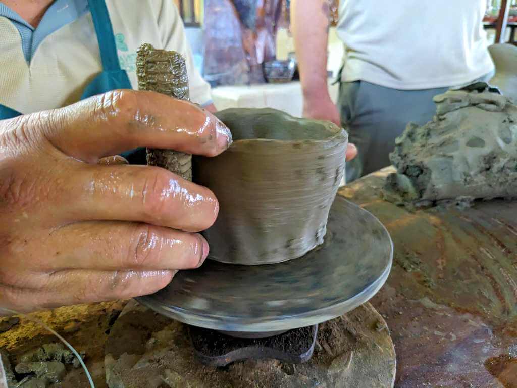 Close-up of a craftsman’s hands shaping clay to form new pottery.