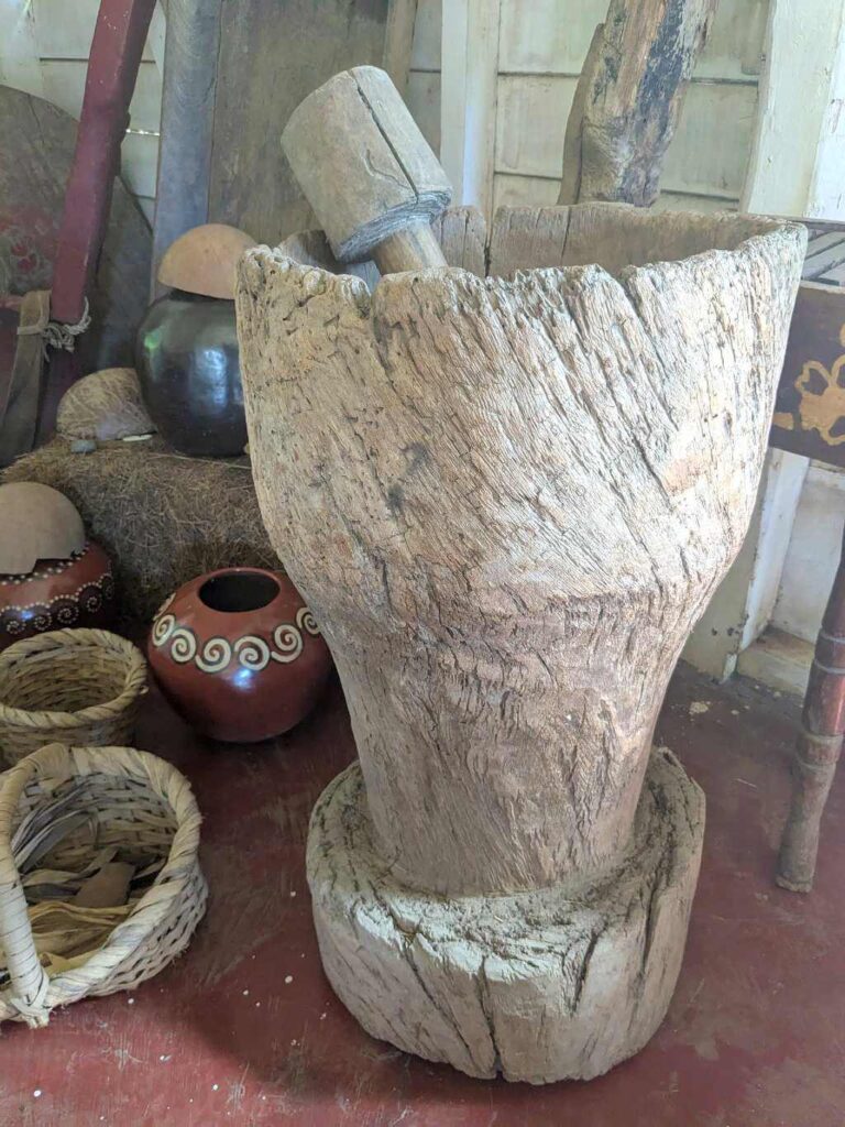 Traditional pilón used for grinding rice, with basins and baskets, reflecting Costa Rican agricultural history.