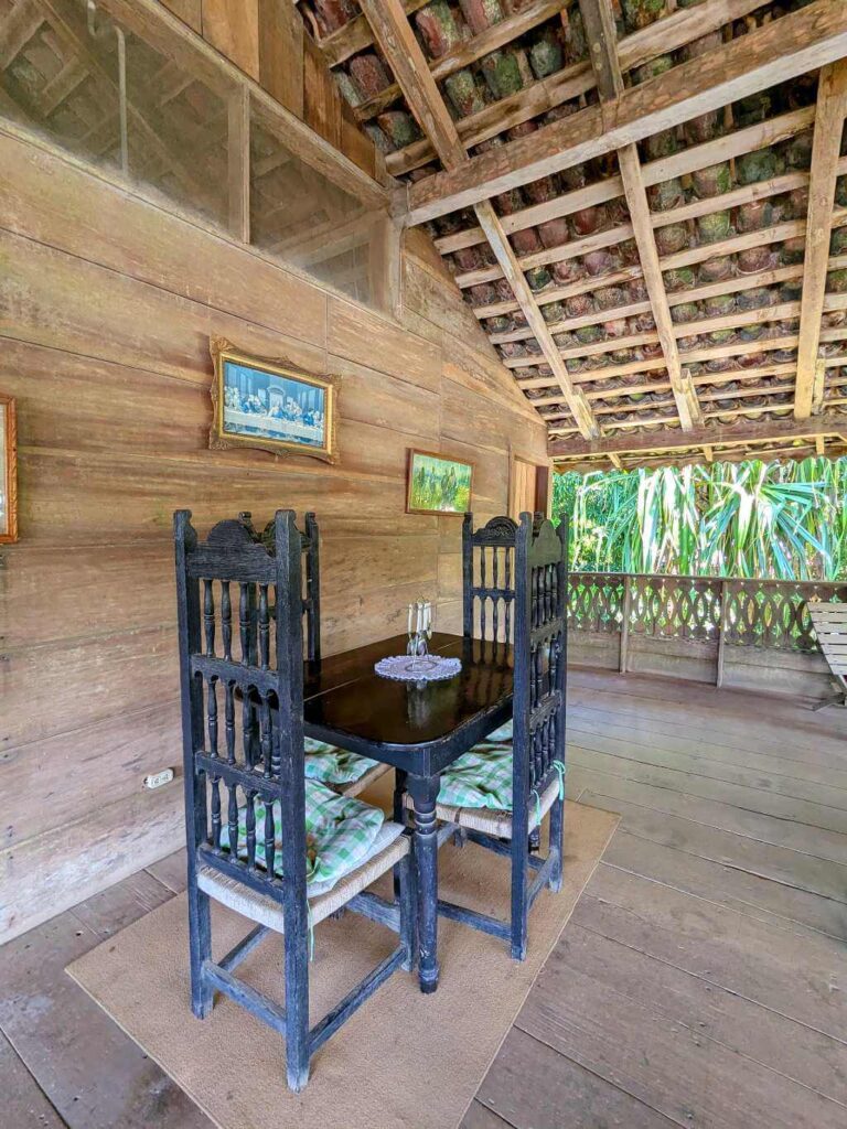 Black wooden table and chairs in a rustic living room with a traditional tile roof.