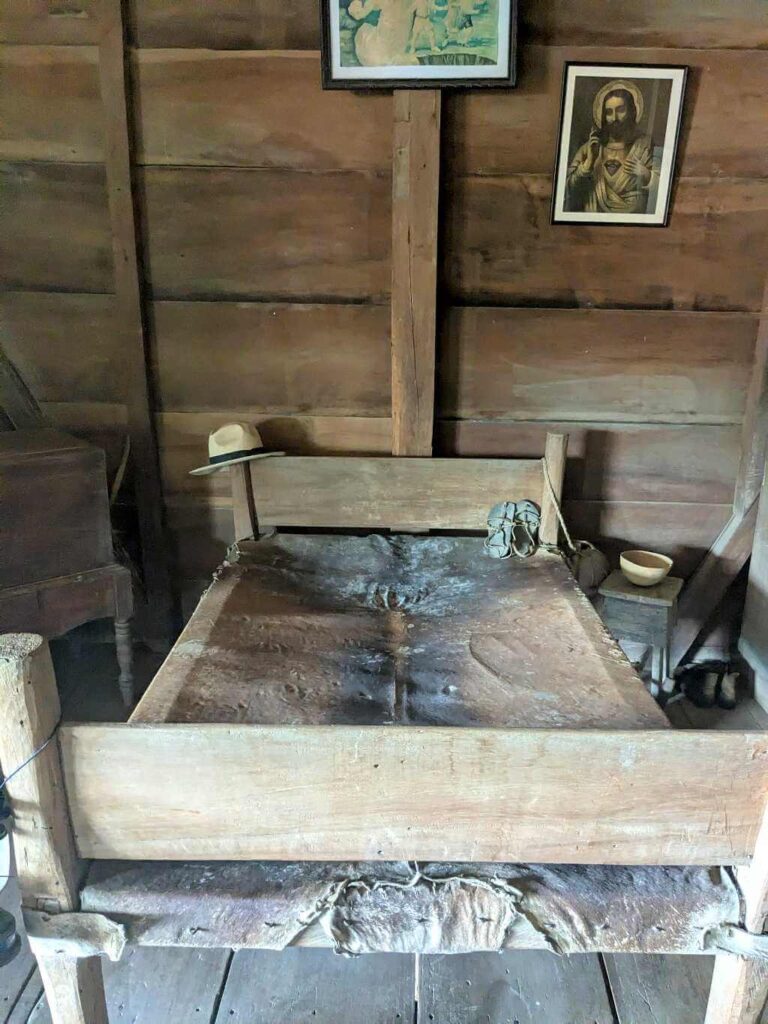 Rustic bedroom with a bed, rustic structure, and a small nightstand.