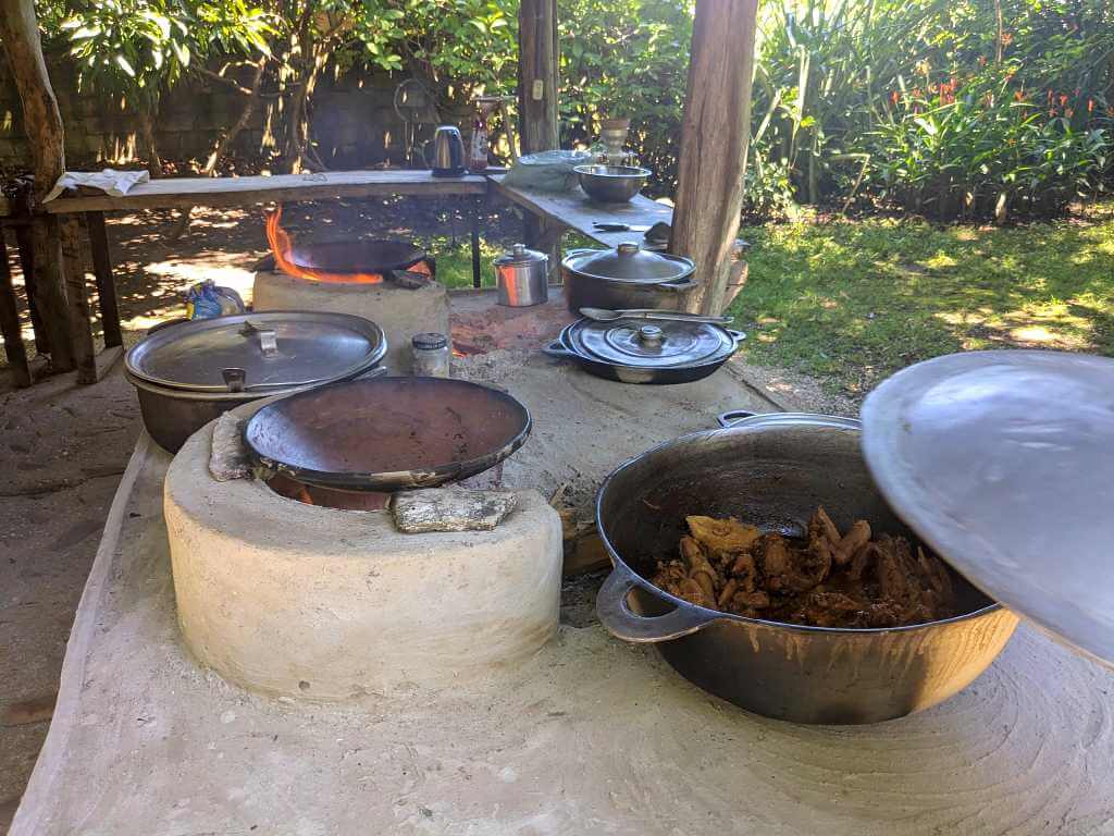 Traditional wood-fired stove with multiple cooking spaces and a pot of chicken in sauce, a typical Costa Rican meal